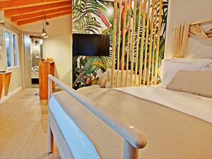 A bedroom with a bed, wooden headboard, and a tropical-themed wall mural.