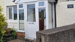 A wellhouse cottage with a white exterior, a small porch, and a metal gate. - Cheerful two bedroom cottage in the Forest of Dean (Ruardean)