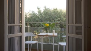 Un balcon ouvert avec une table, deux chaises, un vase de fleurs et une bougie.