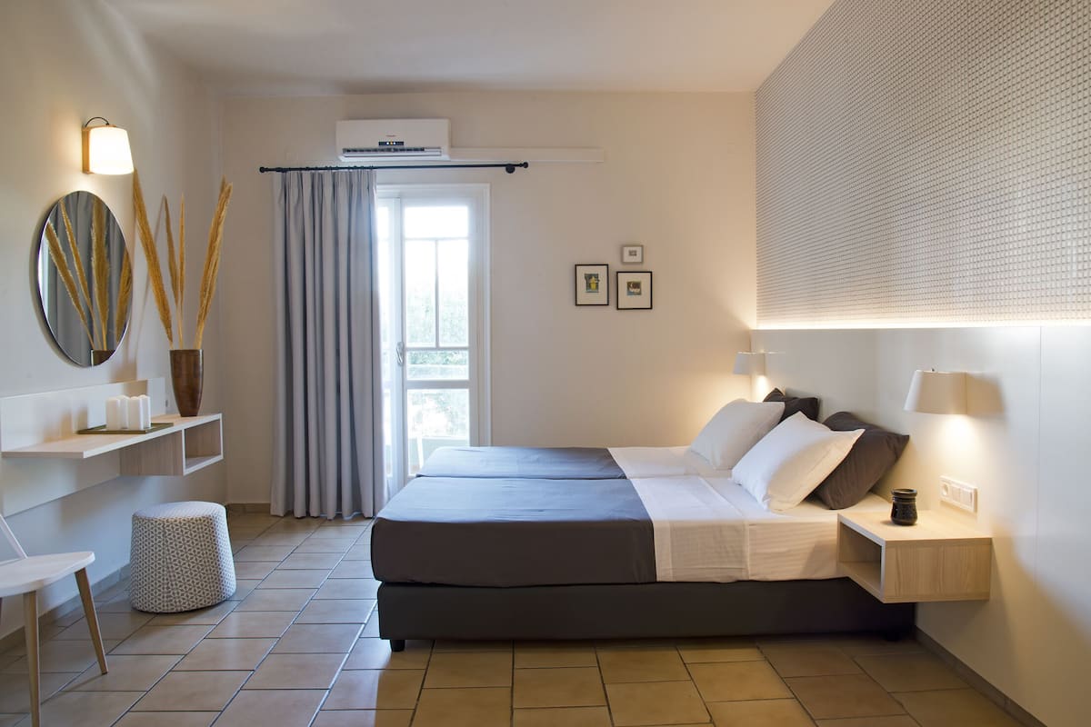 Ein modernes Schlafzimmer mit einem Bett, Nachttischen, einem Spiegel und einem Fenster mit Vorhängen.