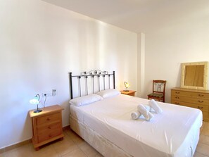 Une chambre à coucher avec un lit, des tables de chevet, une commode et un miroir.