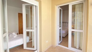 Habitación de hotel con una cama, una puerta de madera y una puerta corrediza de vidrio que da a un balcón.