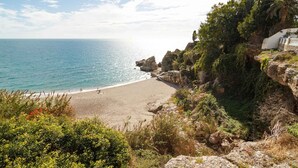 Una playa costera con acantilados rocosos y vegetación.