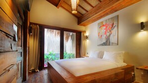 Camera da letto con struttura in legno, un grande letto, una porta scorrevole in vetro a un balcone e un quadro appeso al muro.