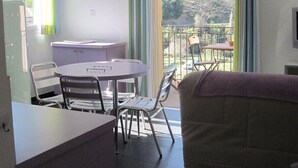 A room with a dining table and chairs, a sofa, a window with curtains, and a clock on the wall. - NICE APARTMENT IN HAMLET 700 M / north pond, fiber, solar hot water (Santa-Lucia-Di-Mercurio)