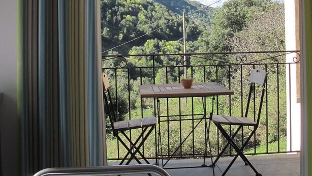 A balcony with a table and chairs, offering a view of a mountainous landscape. - NICE APARTMENT IN HAMLET 700 M / north pond, fiber, solar hot water (Santa-Lucia-Di-Mercurio)