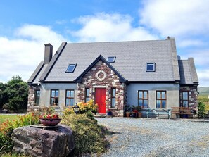 A two-story house with a stone facade, a red door, and a gravel driveway. - Stone fronted detached cottage just over 2 miles from Mulranny village (Mulranny)