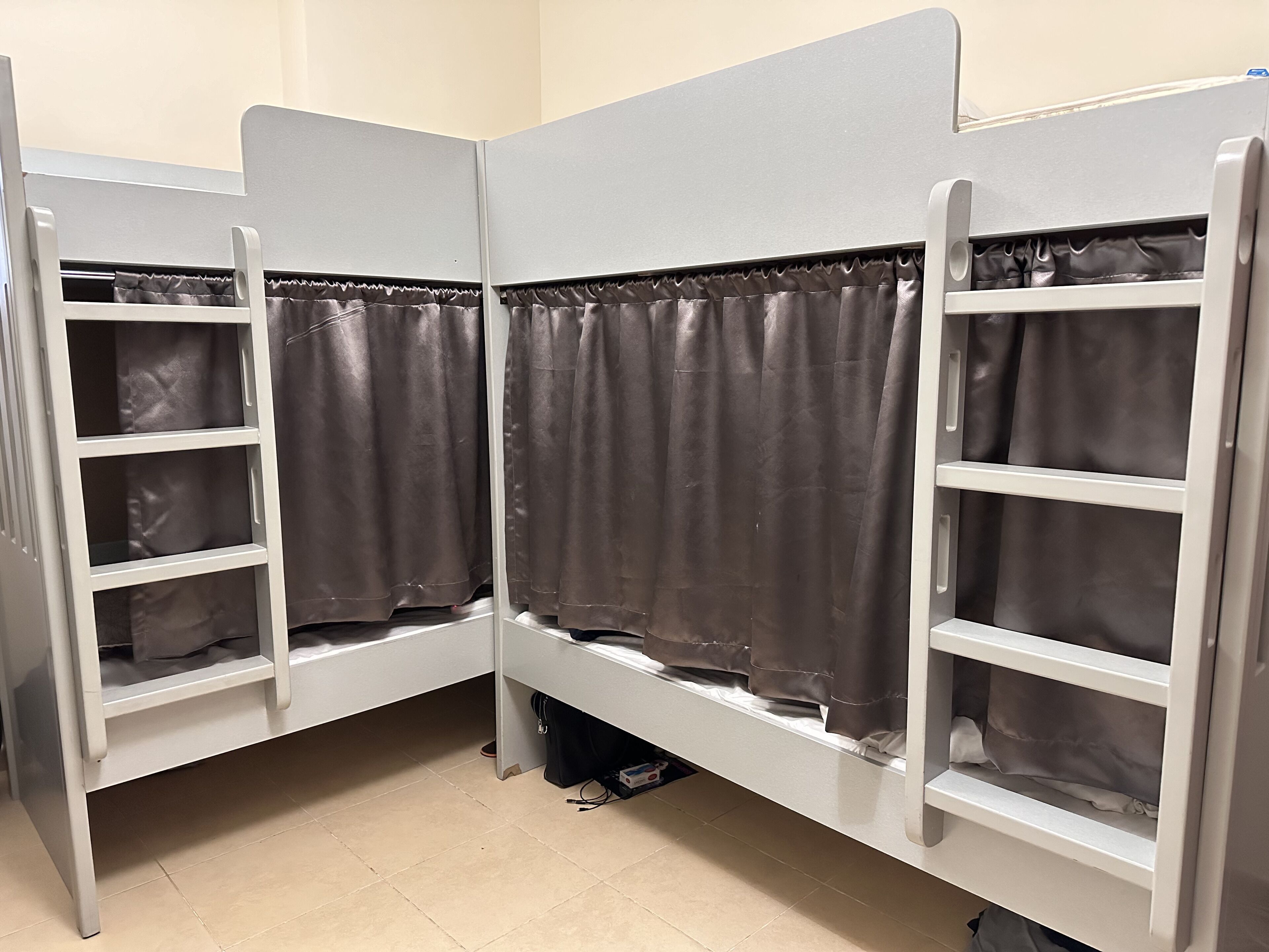 A bunk bed room with curtains, a small table, and a power outlet.