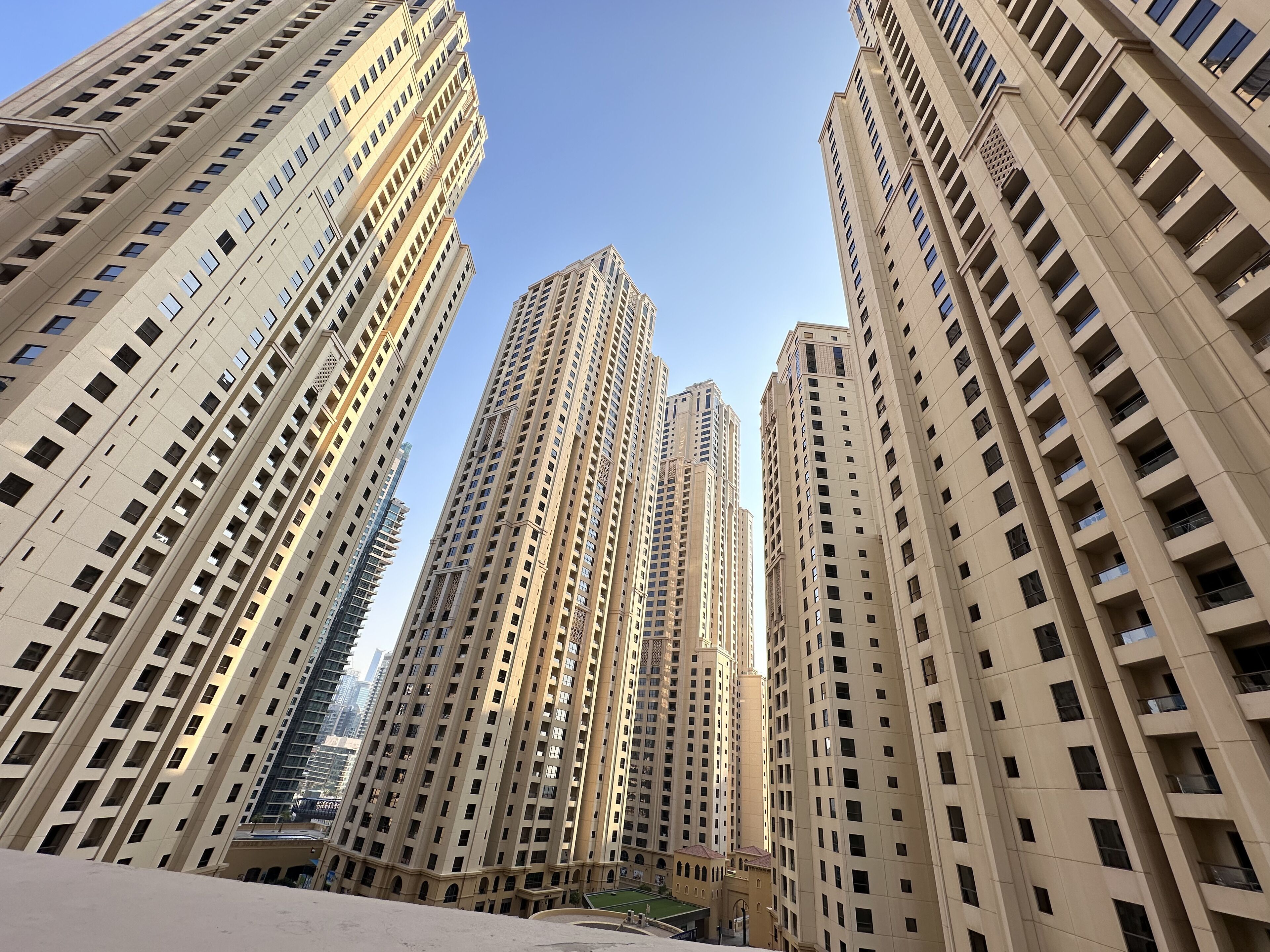 A high-rise building with multiple floors and balconies, surrounded by other tall buildings.