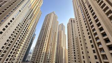 A high-rise building with multiple floors and balconies, surrounded by other tall buildings.
