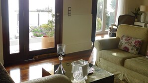 Ein Wohnzimmer mit einer Couch, einem Couchtisch, einer Glasvase und Blick ins Freie durch eine Tür.