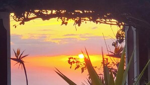 Ein Sonnenuntergang durch einen Durchgang, im Vordergrund tropische Pflanzen.