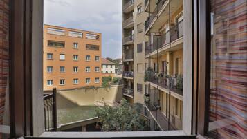 A view from a window overlooking a courtyard with a building featuring balconies and a flat roof.