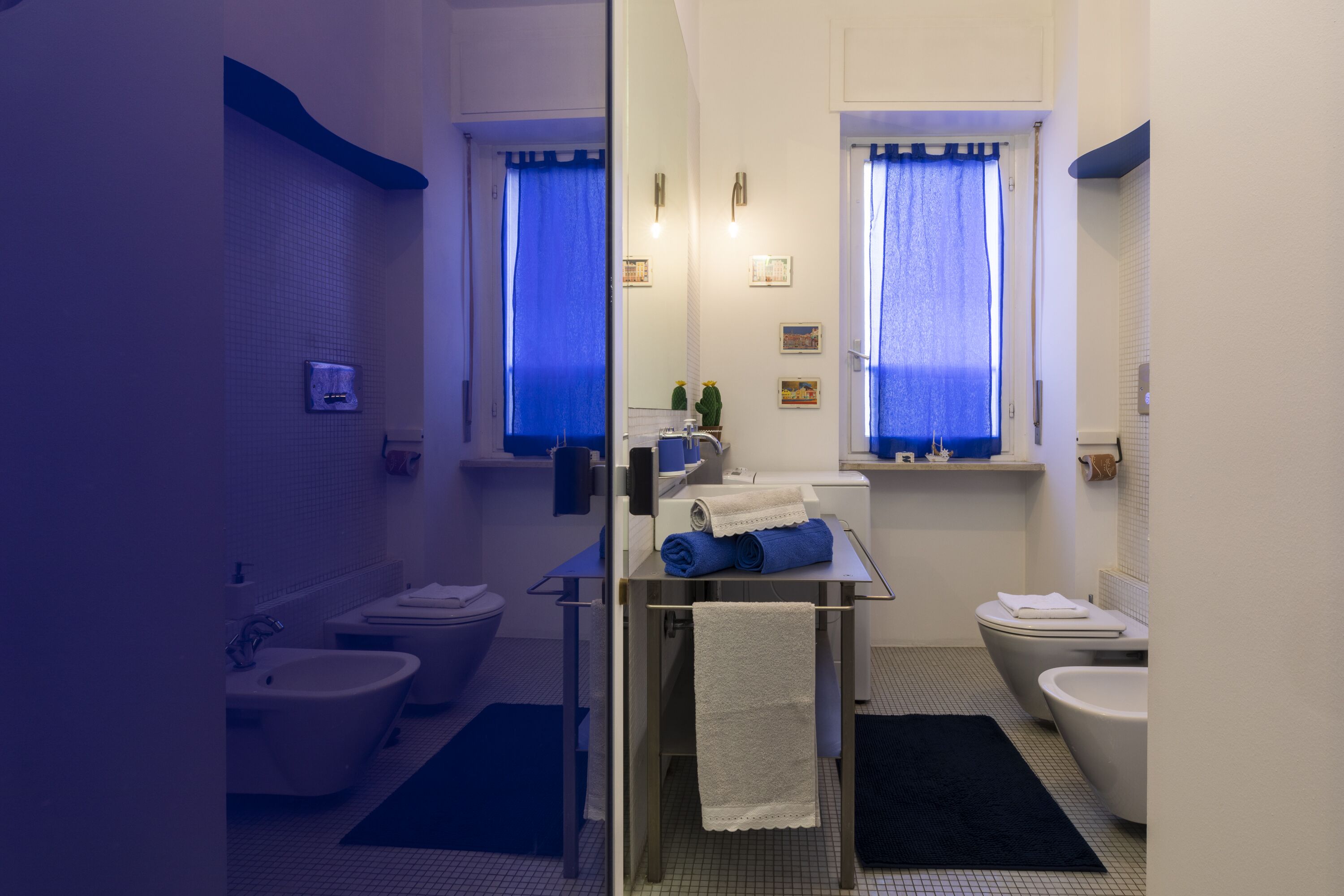 Une salle de bain moderne équipée d’un bidet, de toilettes et d’un lavabo. On trouve des serviettes sur le comptoir et un tapis de bain noir sur le sol.