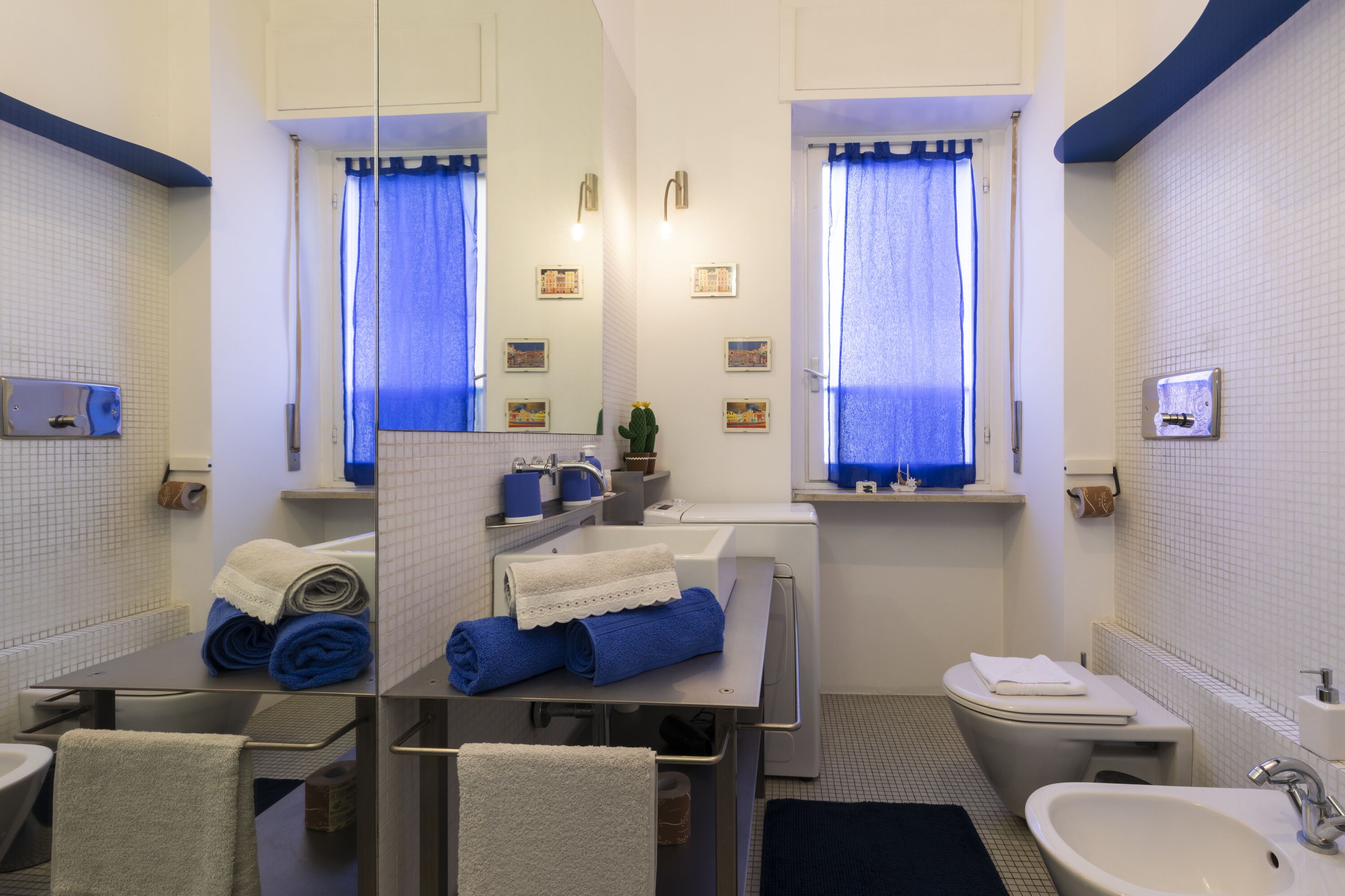 A modern bathroom with a sink, toilet, and mirror. There are towels and toiletries on the counter.