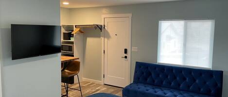 Quarto com cama, TV, escrivaninha e cadeira, e uma janela.