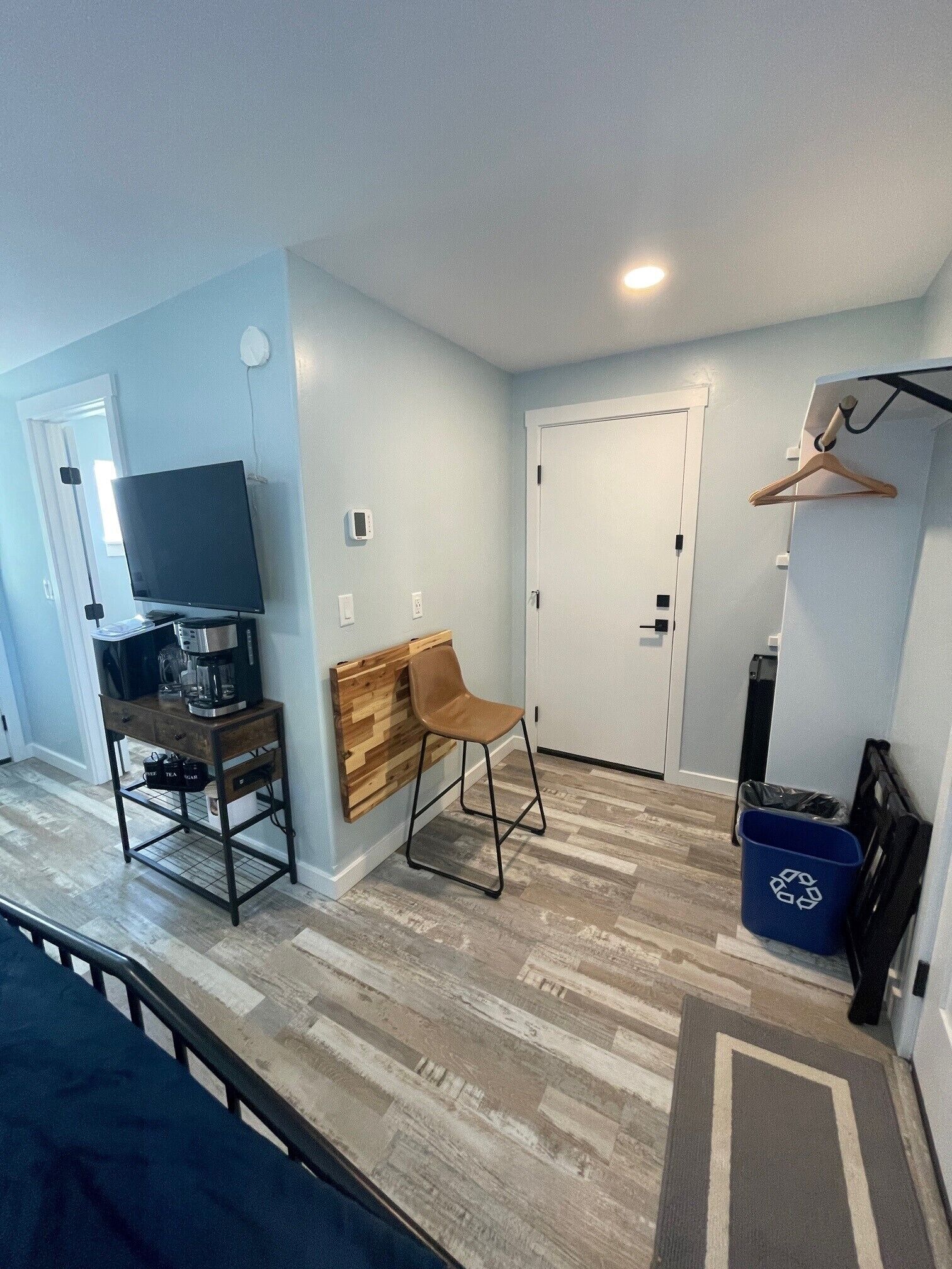 A small, modern room with a wooden desk, a chair, a television, and a door.