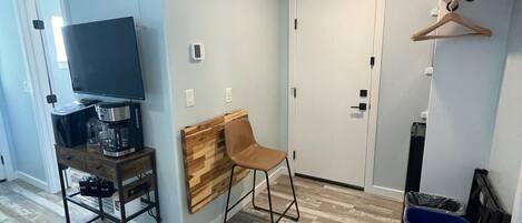 A small, modern room with a wooden desk, a chair, a television, and a door.