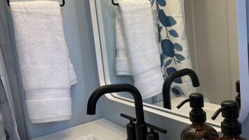 Une salle de bain avec un lavabo blanc, un robinet noir et deux flacons de savon liquide et de lotion pour les mains.