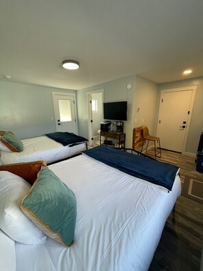 A hotel room with two beds, a TV, a coffee maker, and a chair.