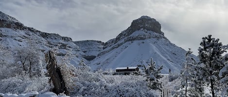 Paisaje nevado con una montaña, un edificio y cielo despejado.