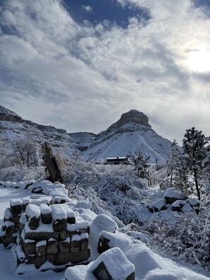 A snow-covered landscape with a mountain, a building, and a clear sky.