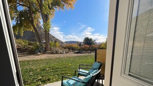 Une terrasse avec un fauteuil et une table, un arbre et une vue sur le paysage.