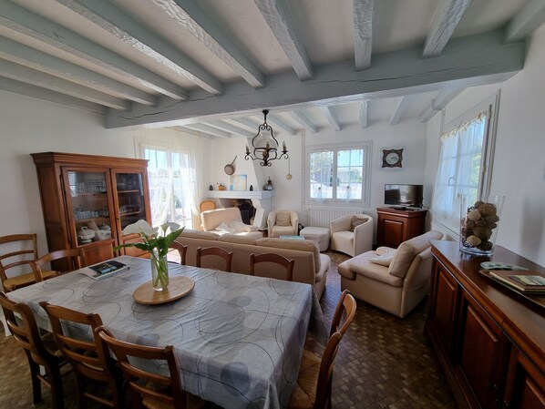 Un comedor con una mesa, sillas y un armario. Hay un sofá y un televisor en la sala.