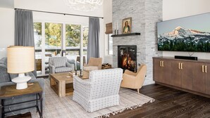 Amplia sala de estar con chimenea, un televisor grande y vistas a la montaña a través de las ventanas.