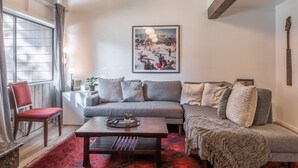 A cozy living room with a grey sofa, a wooden coffee table, and a red patterned rug. - Townhome on the Ski Back Trail! Fireplace! Shared Amenities! (Mammoth Lakes)