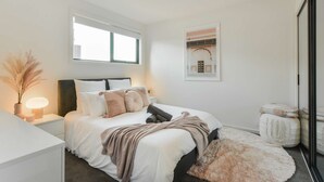 Un dormitorio con cama, mesita de noche, lámpara y un cuadro en la pared.