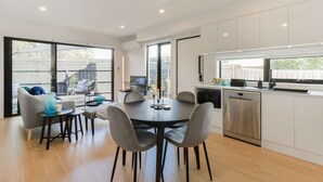 Una cocina moderna con armarios blancos, lavavajillas de acero inoxidable y ventana con vista a un patio trasero.