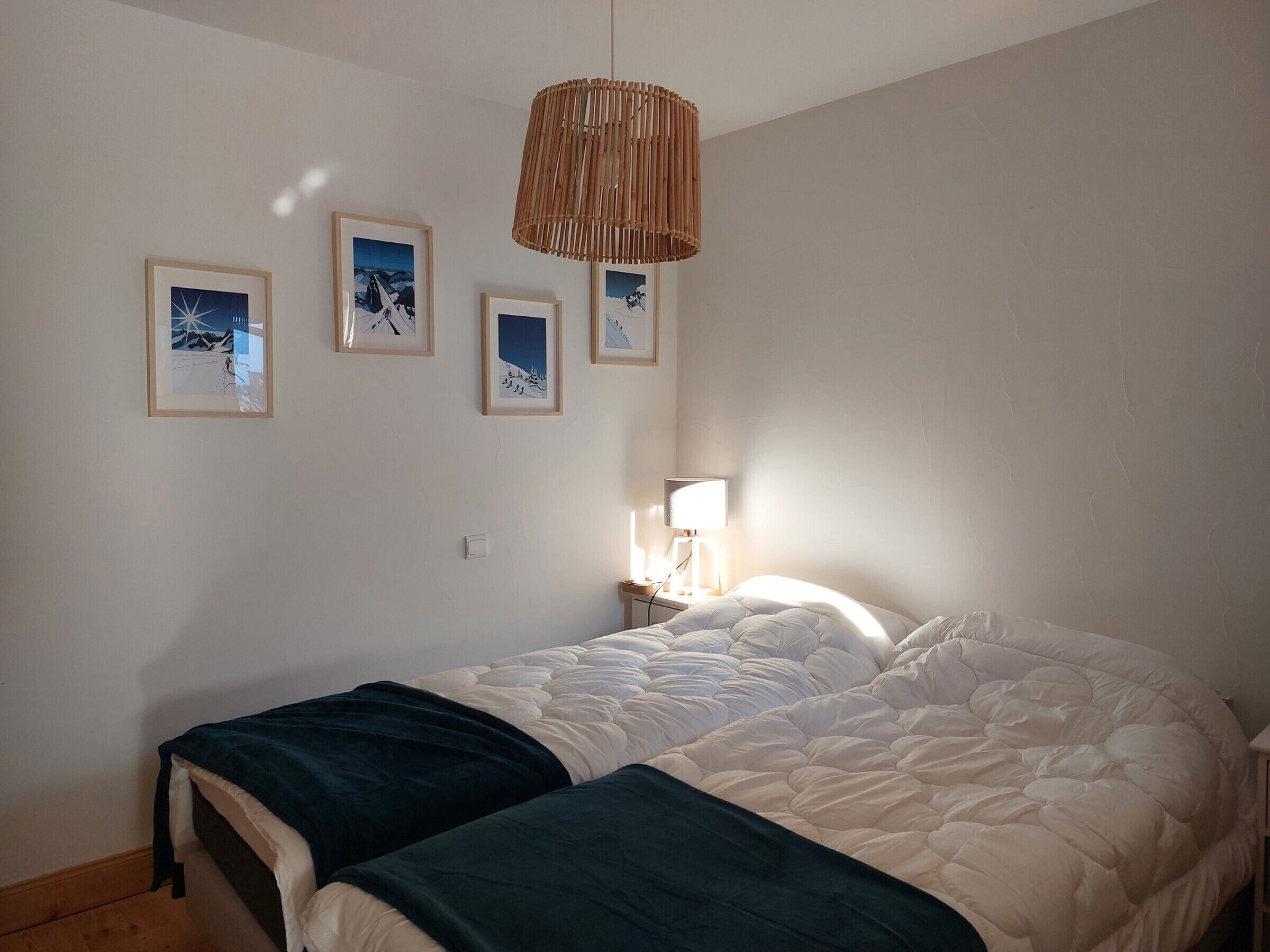 A bedroom with a bed, a bedside lamp, and four framed pictures on the wall.