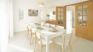 A bright dining area with a white table, white chairs, and a wooden door. - Vacation home Inês by Interhome (Gale)