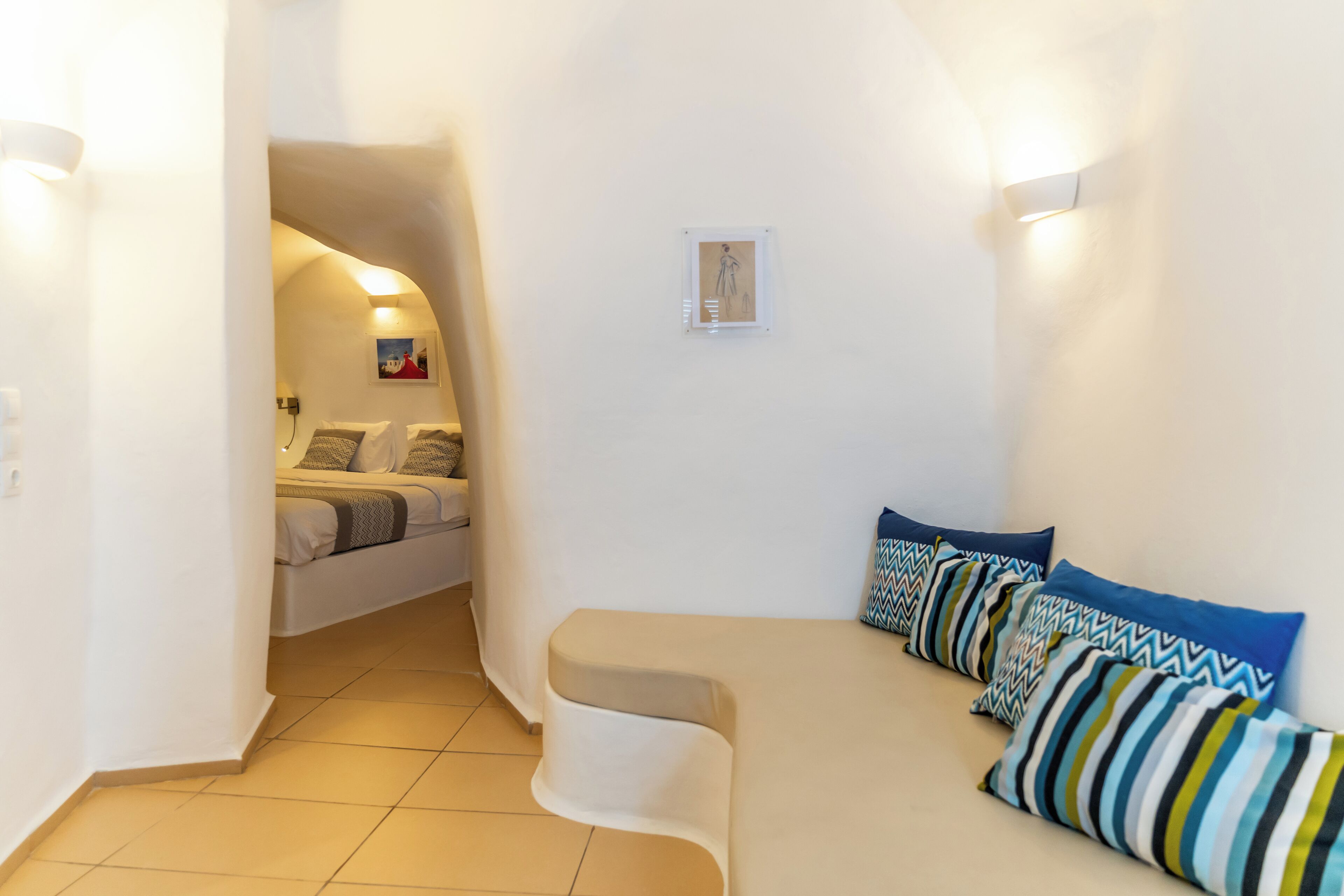 A compact living space with a sofa, a small table, and a bed in the background.