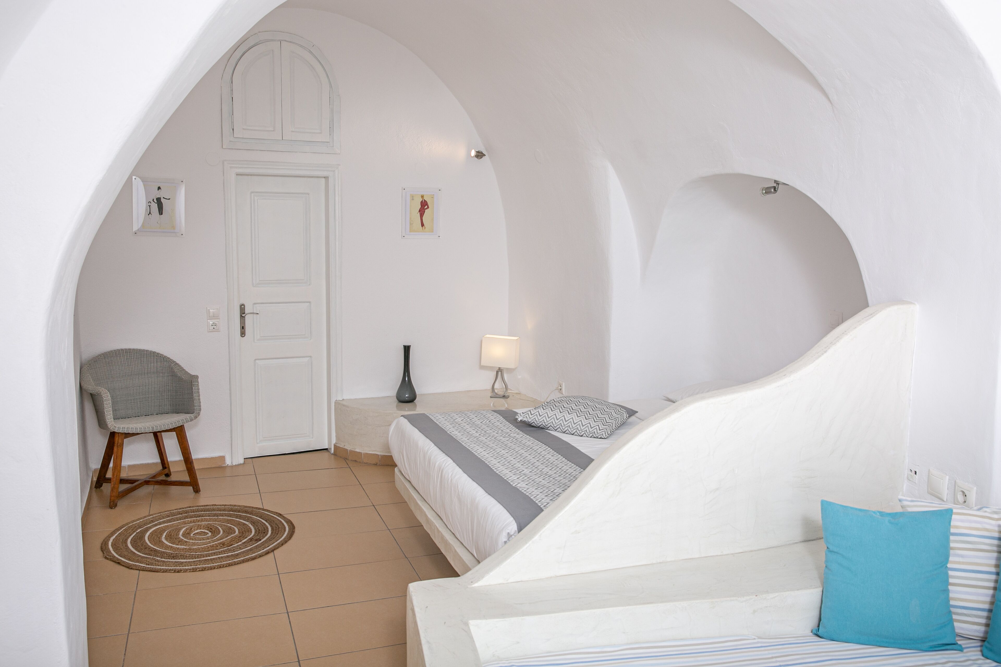Une chambre à coucher avec un lit, une chaise, une table de chevet, une lampe et une porte.