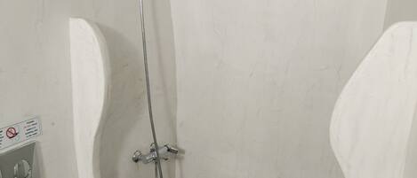 A bathroom with a white toilet, a shower with a handheld showerhead, and a bidet.