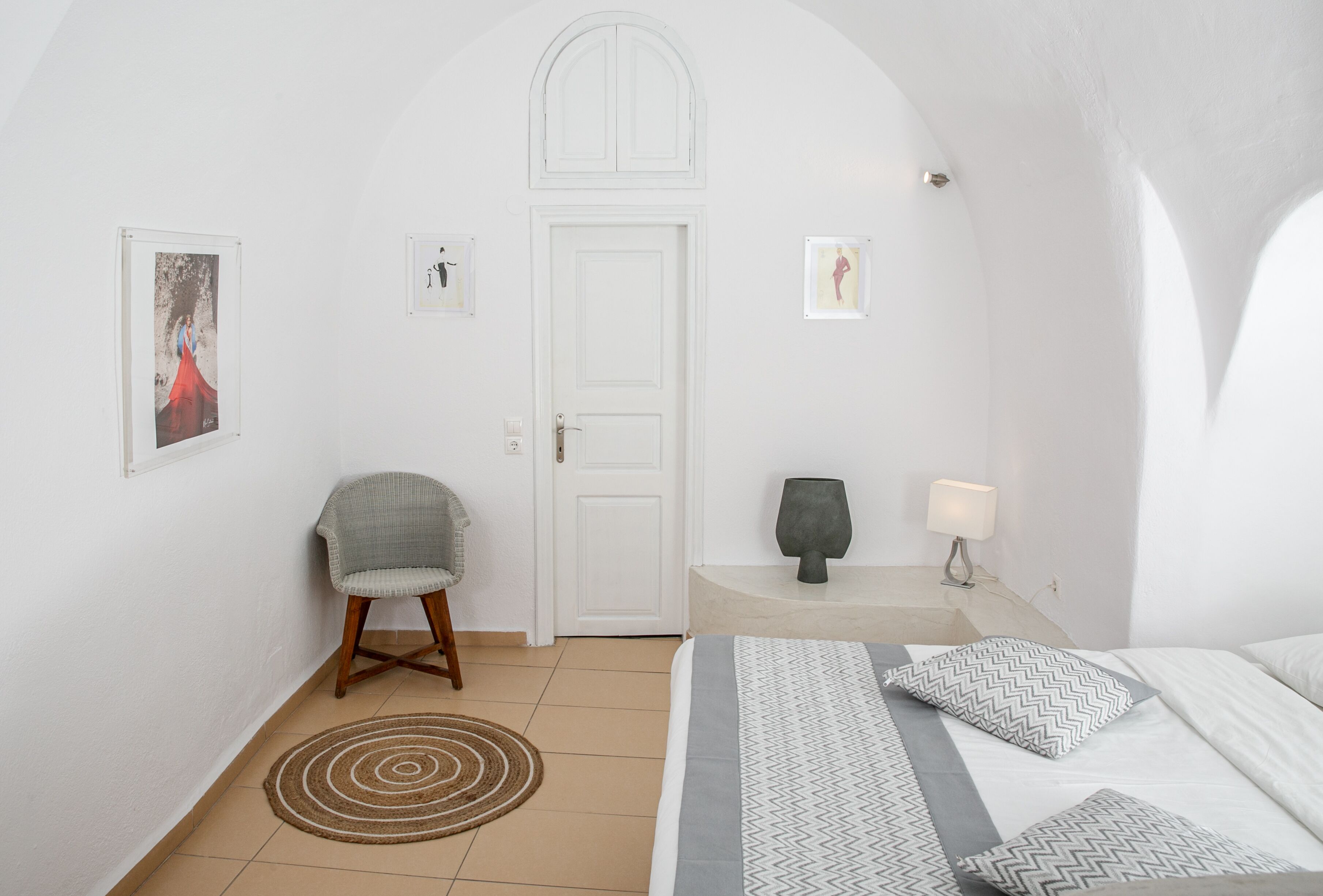 A bedroom with a bed, a chair, a door, and wall-mounted artwork.
