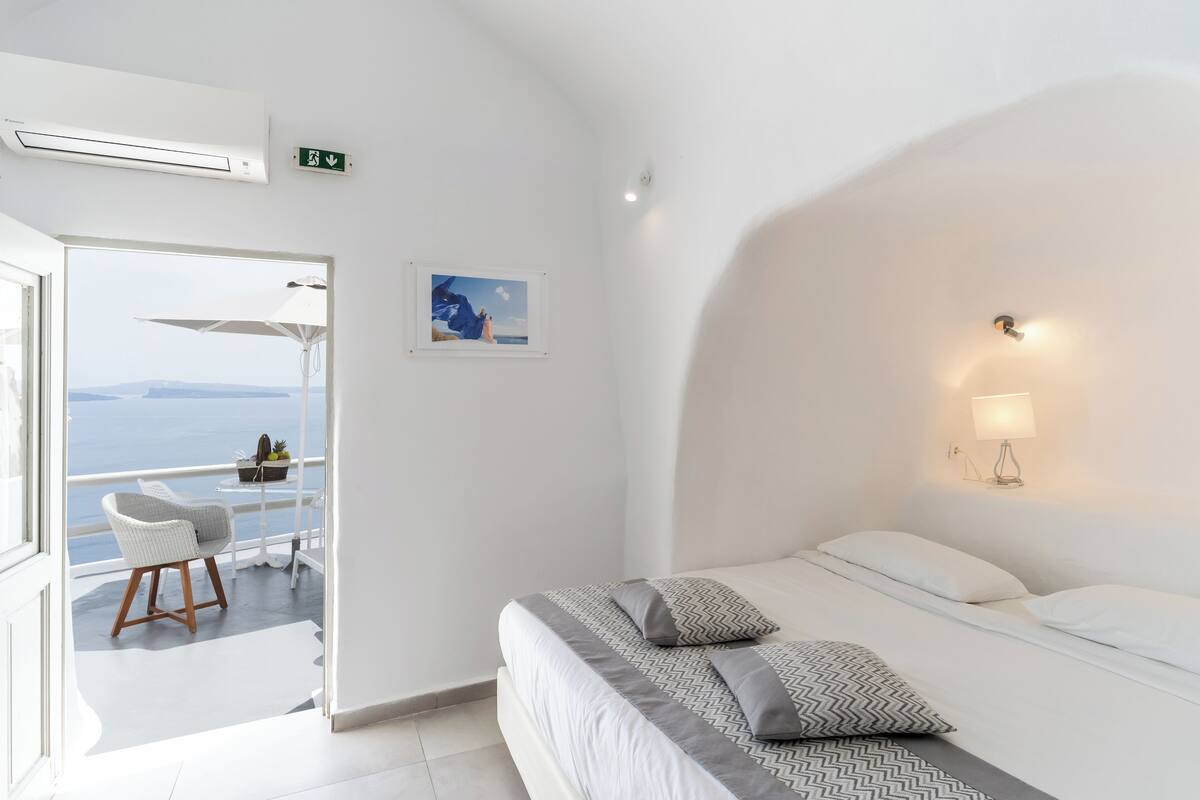 Ein Hotelzimmer mit Bett, Sessel, einem Bild an der Wand und Meerblick.