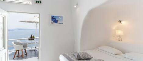 Habitación de hotel con una cama, una silla, un cuadro en la pared y vista al mar.