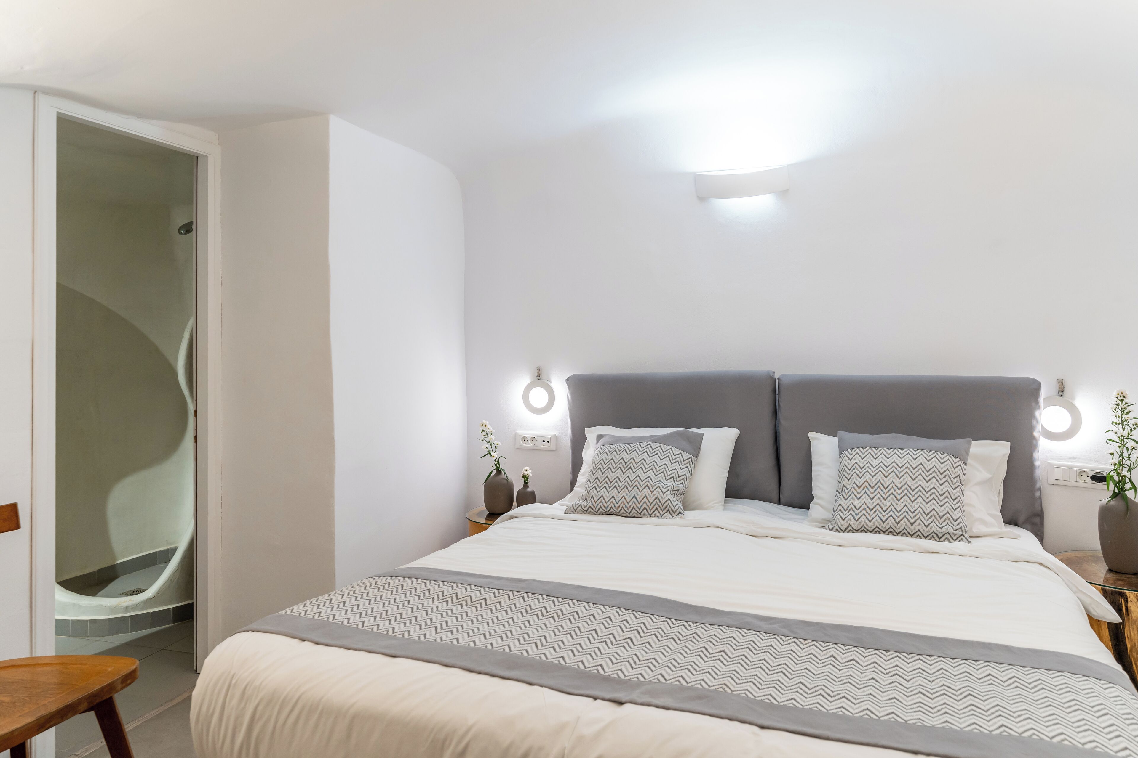 Ein Schlafzimmer mit Bett, Nachttischen, einem Sitzplatz und einer Duschgelegenheit.