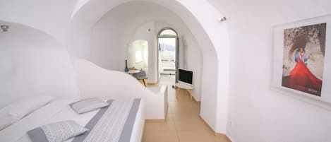 A bedroom with a bed, a TV, and a poster on the wall.