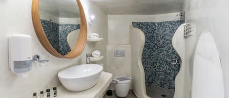 Un baño con un lavamanos blanco, un espejo grande, un inodoro y una ducha con mosaicos azules.