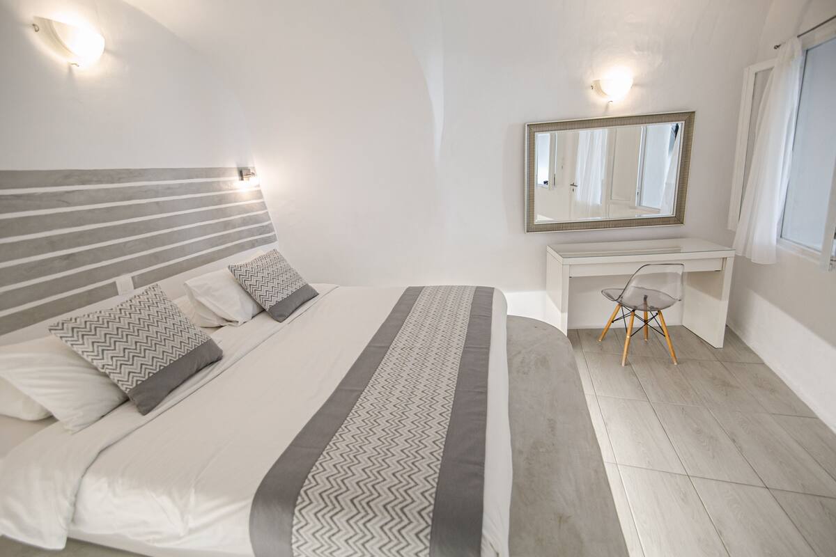 Ein Schlafzimmer mit Bett, Schreibtisch, Stuhl und Spiegel.