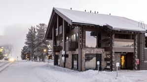 En moderne bygning med en stenfassade, store vinduer og et tag dækket af sne.