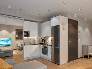 A modern kitchen with a built-in oven, a refrigerator, and a coffee maker.