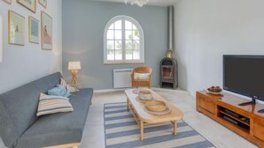 Una sala de estar con un sofá, una mesa de centro de madera, un televisor, una chimenea y cuadros en la pared.