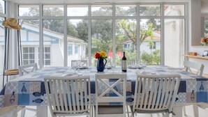 Un comedor con una mesa lista para dos personas, ventanas grandes y vistas de los edificios circundantes.