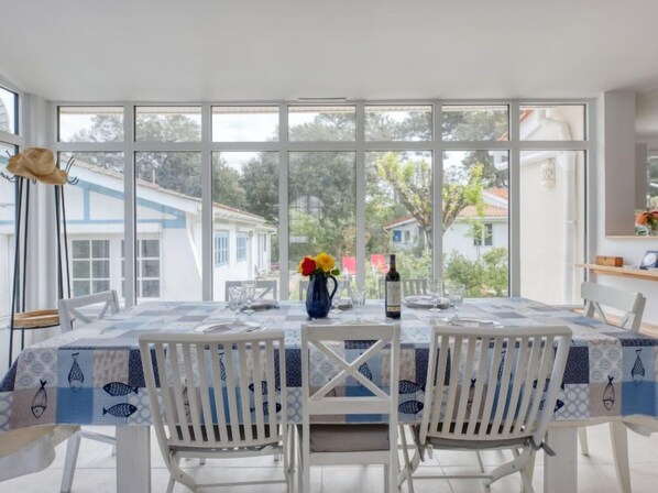 A dining area with a table set for two, large windows, and a view of the surrounding buildings.