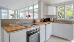 Una cocina moderna con armarios blancos, encimera de madera, horno empotrado, microondas y lavabo.